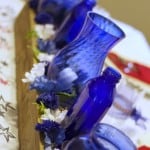 Blue bottles and flowers in a fence slat box for table centerpiece