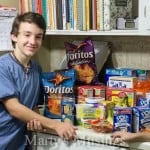 boy in blue shirt leaning against counter with groceries on it