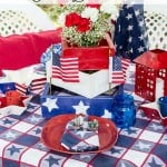 Inexpensive 4th of July table decorations from yard sales, thrift stores and around the home with seasonal flowers create a perfect rustic, outdoor setting.