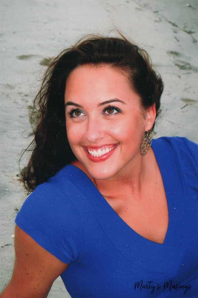 Young woman in blue shirt on beach looking at camera