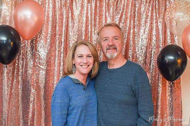 Husband and wife with pink and silver backdrop and black, clear and pink balloons