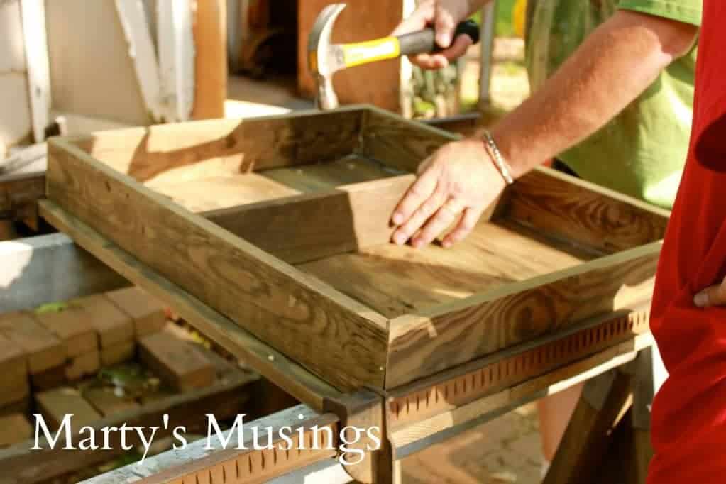 A man cooking food on a table, with Wood and Fence