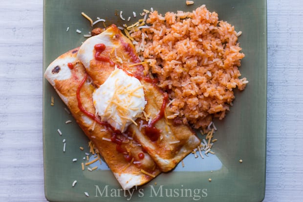 A plate of food with a fork and knife, with Enchilada