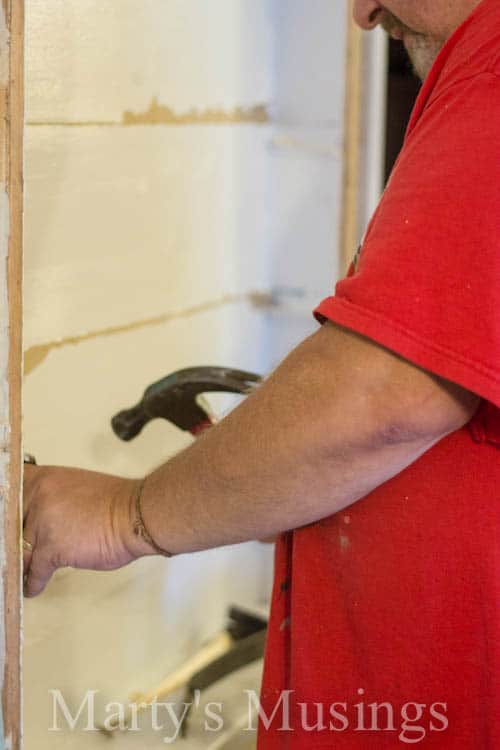 Man with red shirt hammering nails in wall