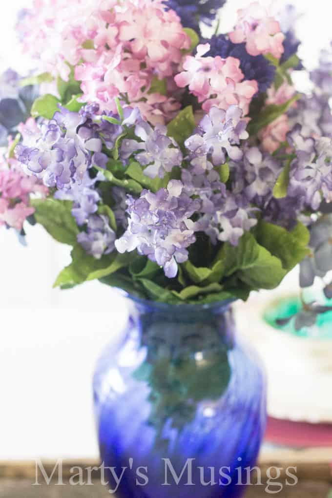 A close up of a vase with a purple flower