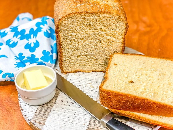 sliced homemade white bread with butter and blue napkin