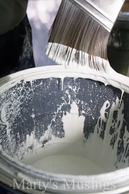 Dripping paint on brush over can of paint