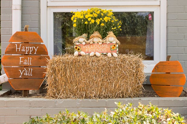 Front flower bed with hay and orange wooden pumpkins for fall