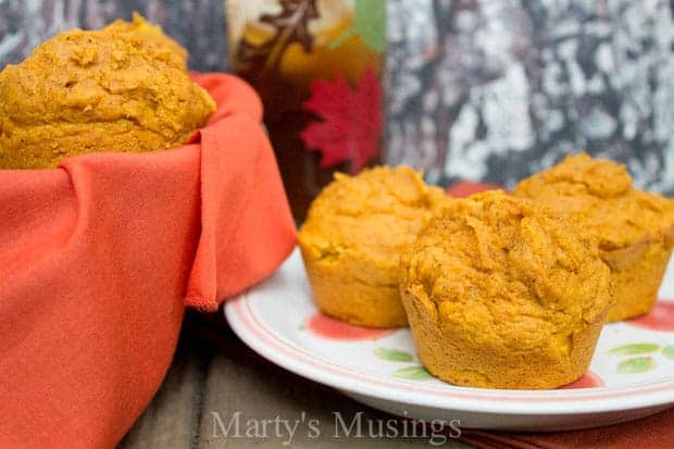 Plate with pumpkin muffins and basket with glass of tea