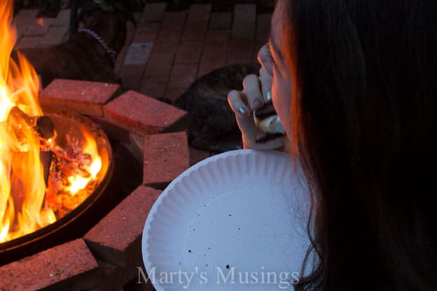 A person standing in front of a fire, with Milky Way