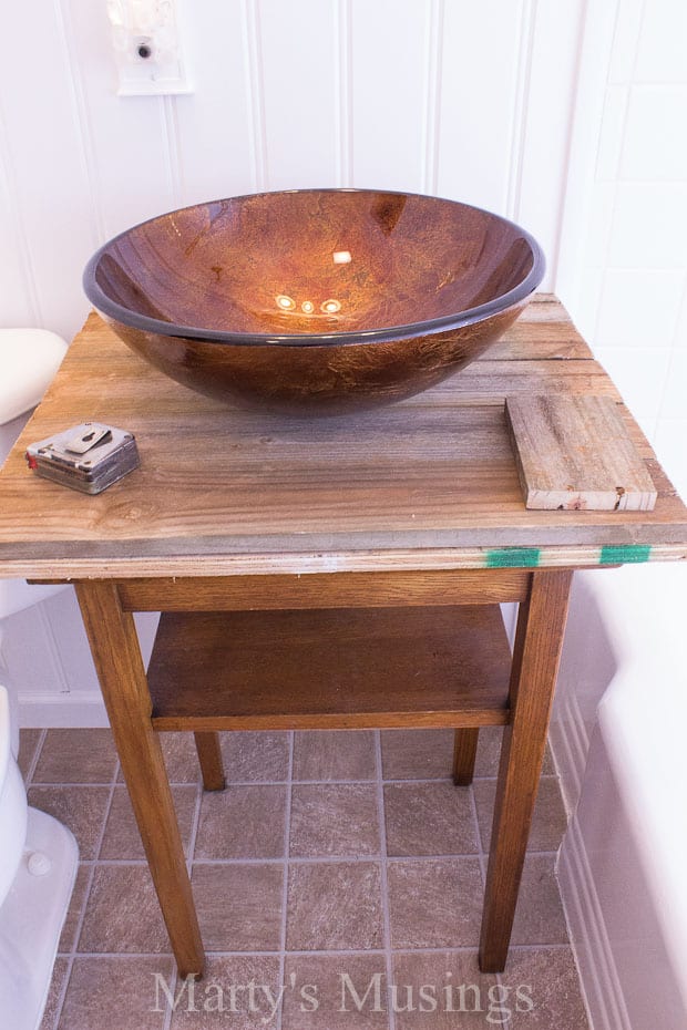 A brown bowl on top of a wooden table, with Bathroom and Fence