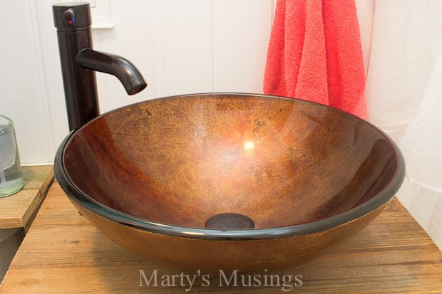 A bowl of soup sitting on top of a wooden table, with Bathroom and Fence