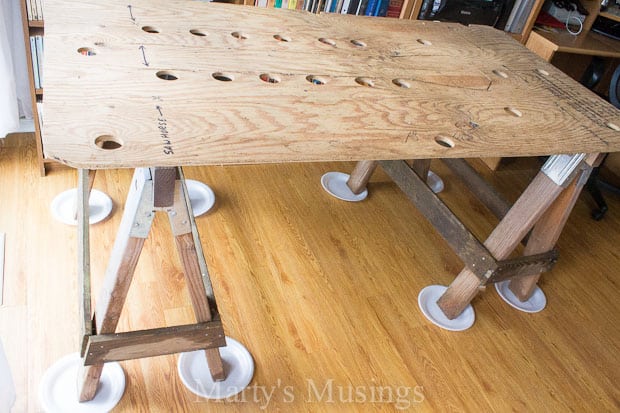 Plywood with holes cut out resting on wooden saw horses and paper plates