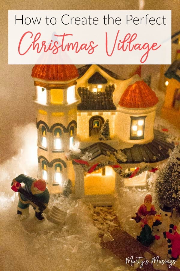 Miniature Christmas village house with people in front lit up at night