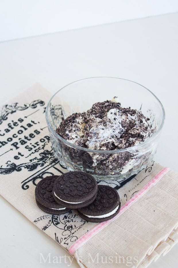 Oreo Dirt Cake shown on counter with oreos on the side in glass bowl