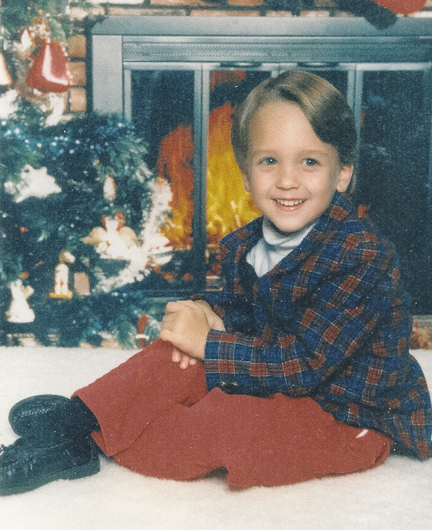 A little boy that is sitting in front of a window