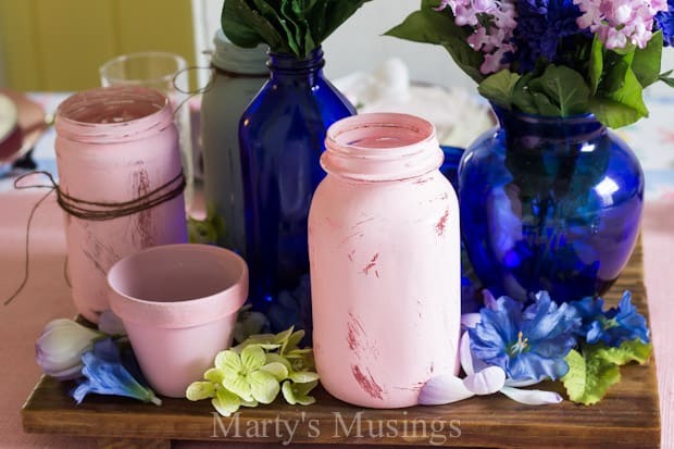 A cup of coffee and a vase of flowers on a table, with Mason jar