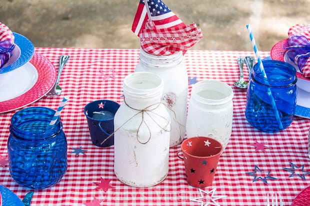 A cup of coffee sitting on top of a picnic table, with Napkin and Jar