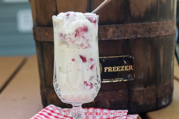 A glass of wine sitting on top of a wooden table, with Ice cream