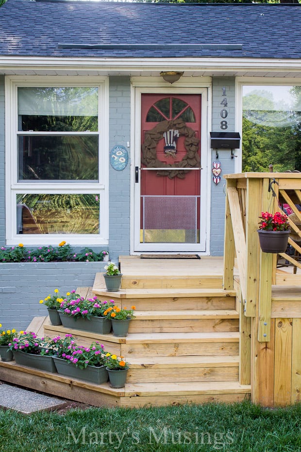 Unstained front deck with stairs and flowers