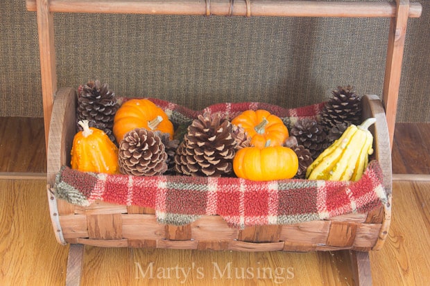 A bowl of fruit sitting on top of a wooden table, with Basket and Gourd