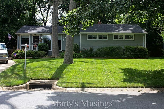 Ranch style house with green yard and bushes in front