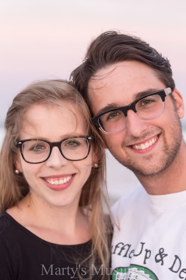 A man and a woman wearing glasses and smiling at the camera