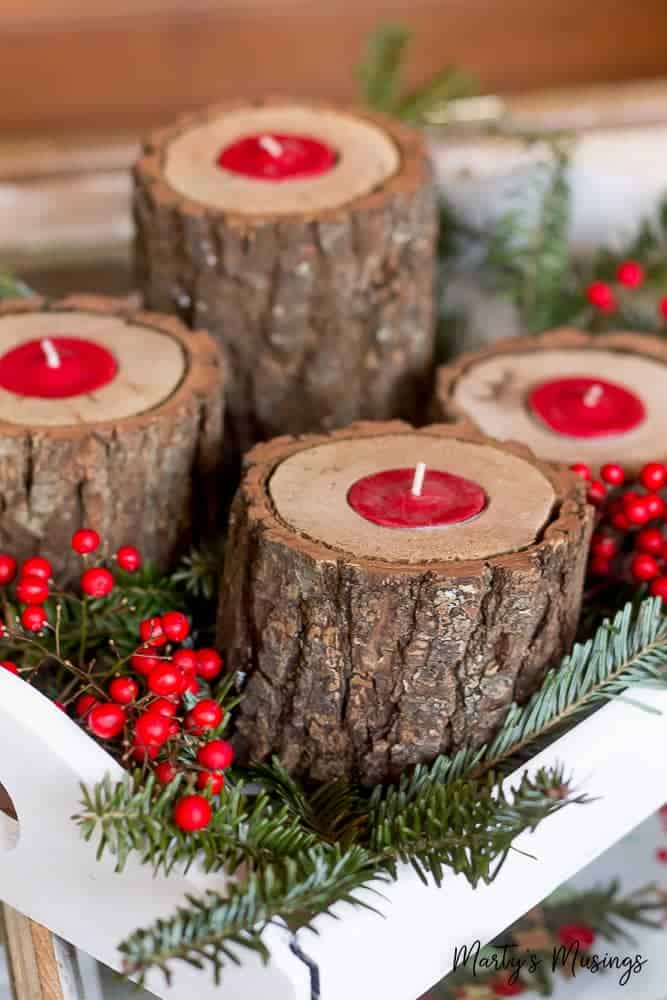 Wooden candle holders on a white tray with greenery and red berries