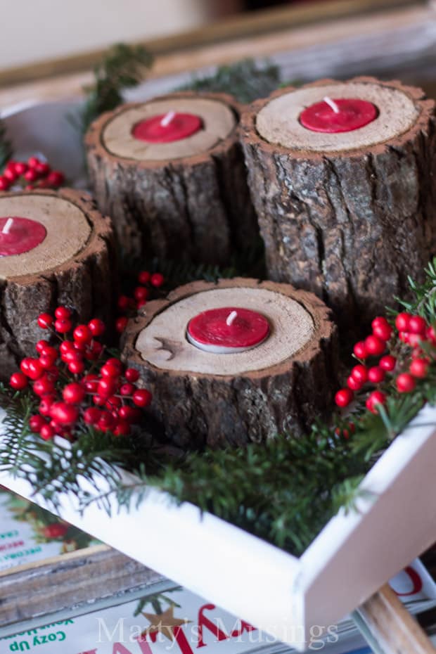 Log candle holders with red tea lights gathered with greenery and red berries