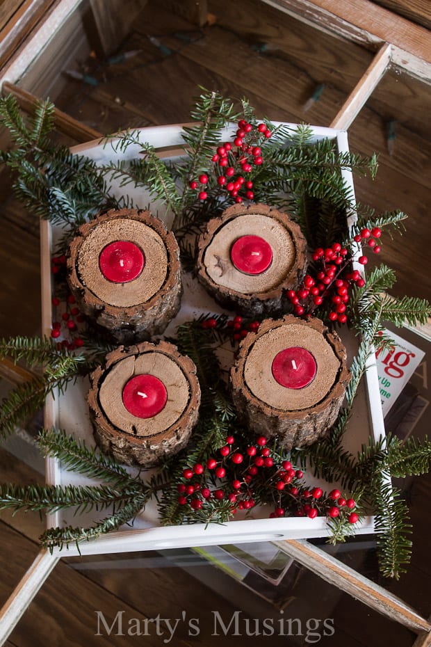Log candle holders with red tea lights and greenery with red berries