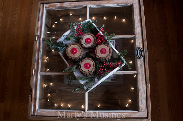 White tray with rustic wood candle holders and greenery placed on window table