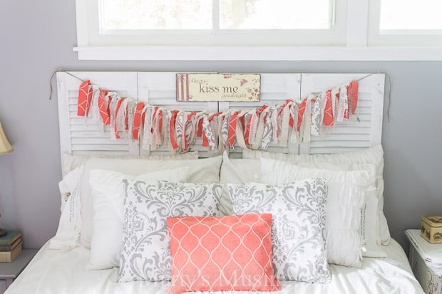 A bedroom with a coral and white fabric banner and pillows