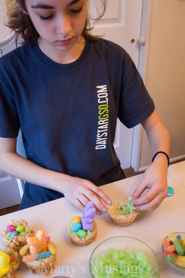 A woman sitting at a table with a plate of food, with Rice Krispies Treats