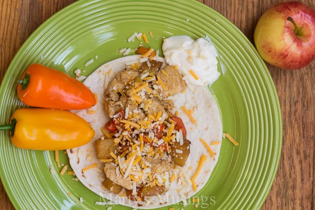 A bowl of food on a plate, with Fruit and Chicken