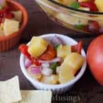 A bowl of food on a table, with Pineapple and Salsa