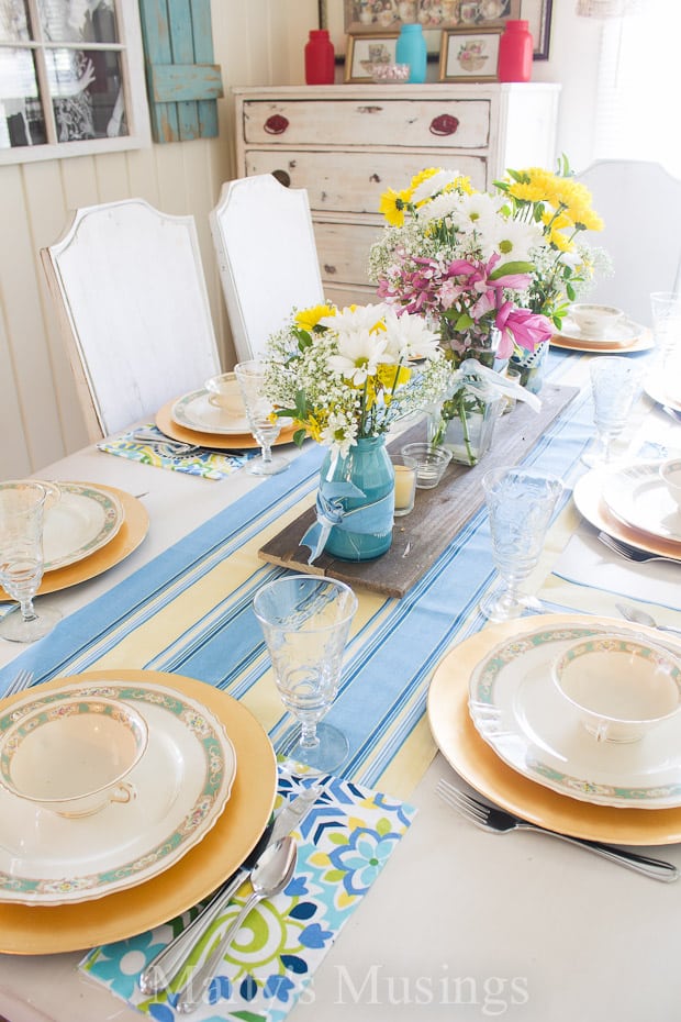 A plate topped with a vase of flowers on a table, with Blue and Yellow