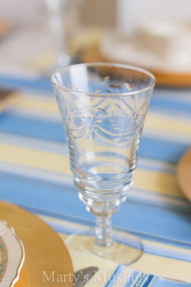 A glass cup on a table, with Blue and Flower