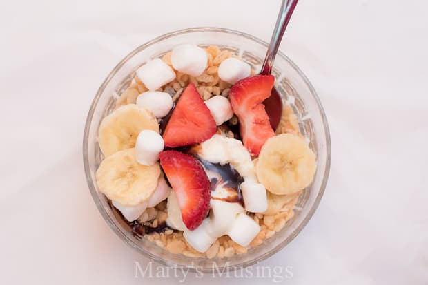 A bowl of fruit on a plate, with Rice Krispies and Ice cream