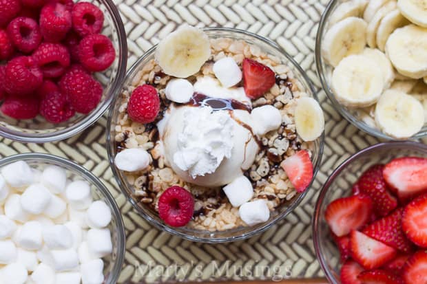 A bowl of fruit on a plate, with Ice cream and Rice Krispies