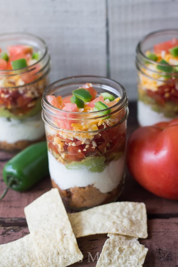 A slice of fresh fruit and vegetables on a cutting board, with Mason jar