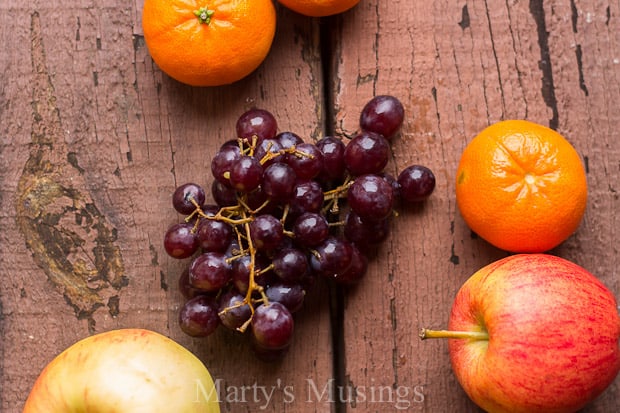 Two oranges sitting on top of a wooden cutting board, with Life and Fruit