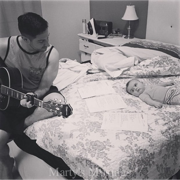 A person sitting on a bed next to a guitar