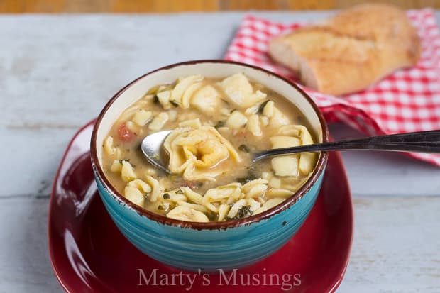 A bowl of food on a plate, with Cheese and Soup