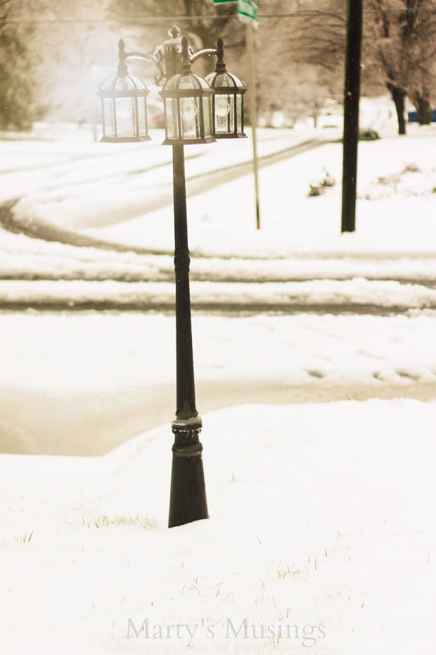 A pole that has a sign on the side of a snow covered street