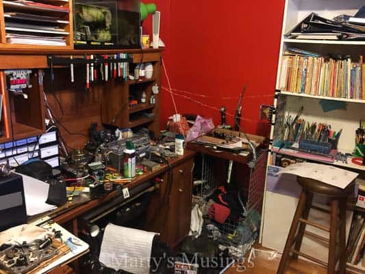 A cluttered desk with a book shelf