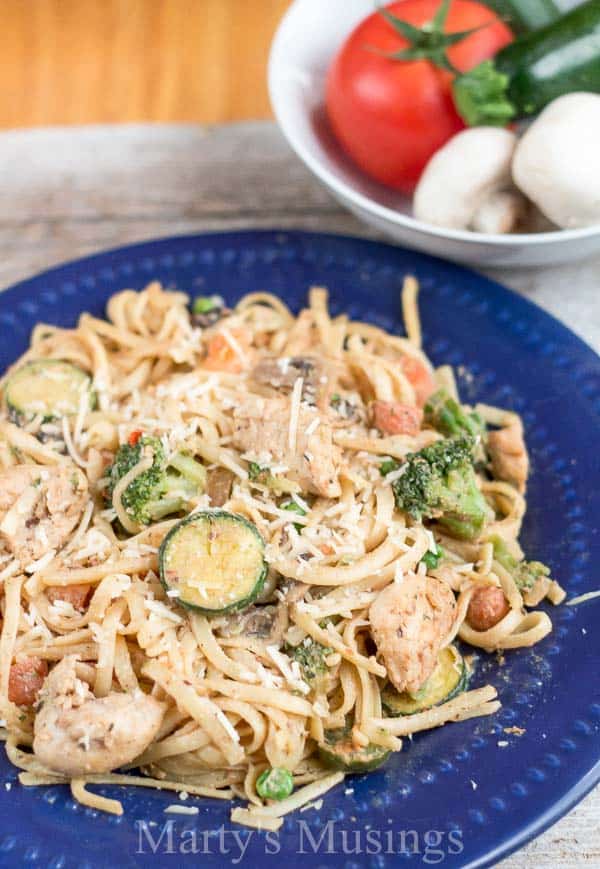 A bowl of pasta with chicken and broccoli on a plate, with Pasta primavera