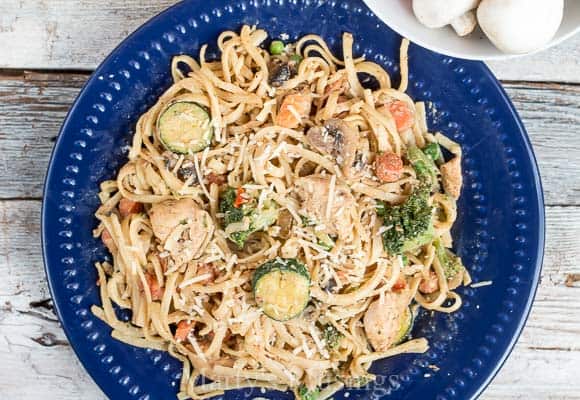 A bowl of pasta salad on a blue plate, with Pasta primavera