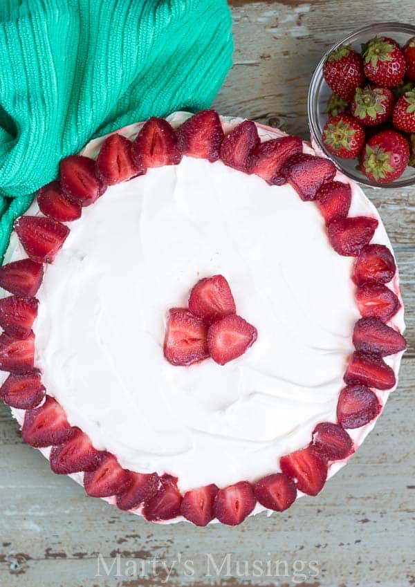 A decorated cake on a plate, with Strawberry