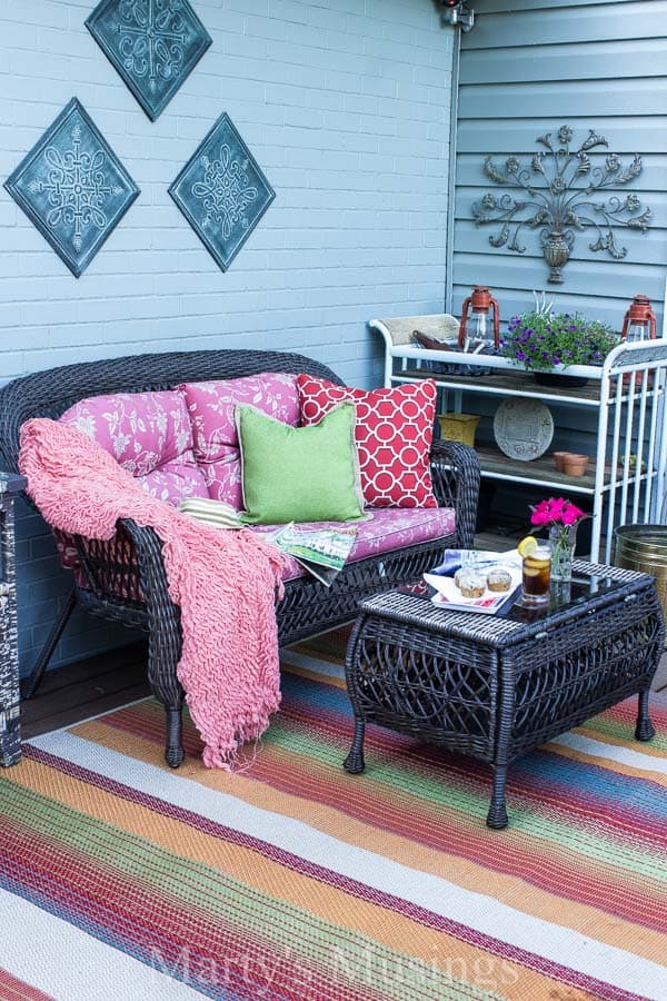 Dark furniture with colorful pillows and rug on front deck