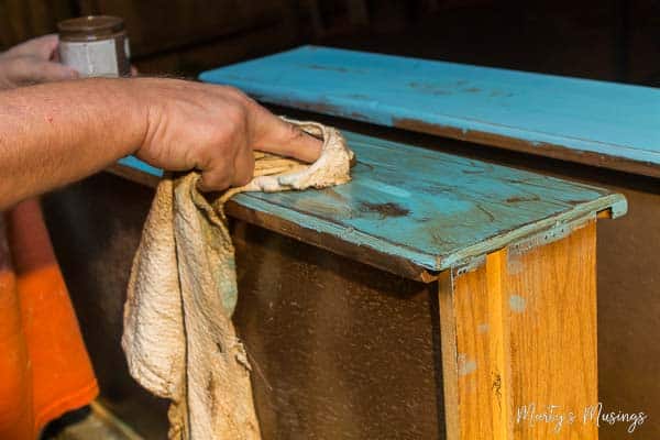 Using old cloth to spread dark wax on dresser drawers